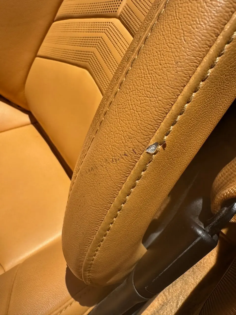 Pale tufted leather cushion with surface flaking and wear