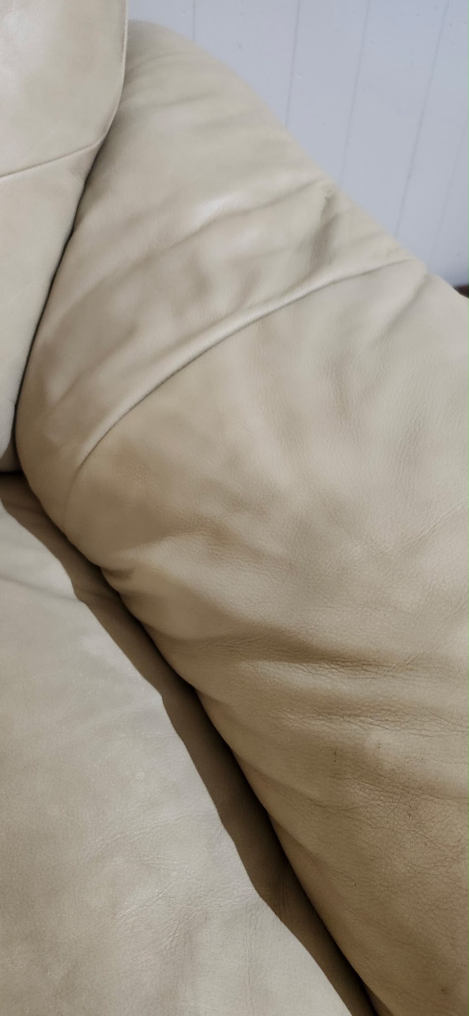 The same beige leather sofa cushion with the worn patch repaired and recoloured