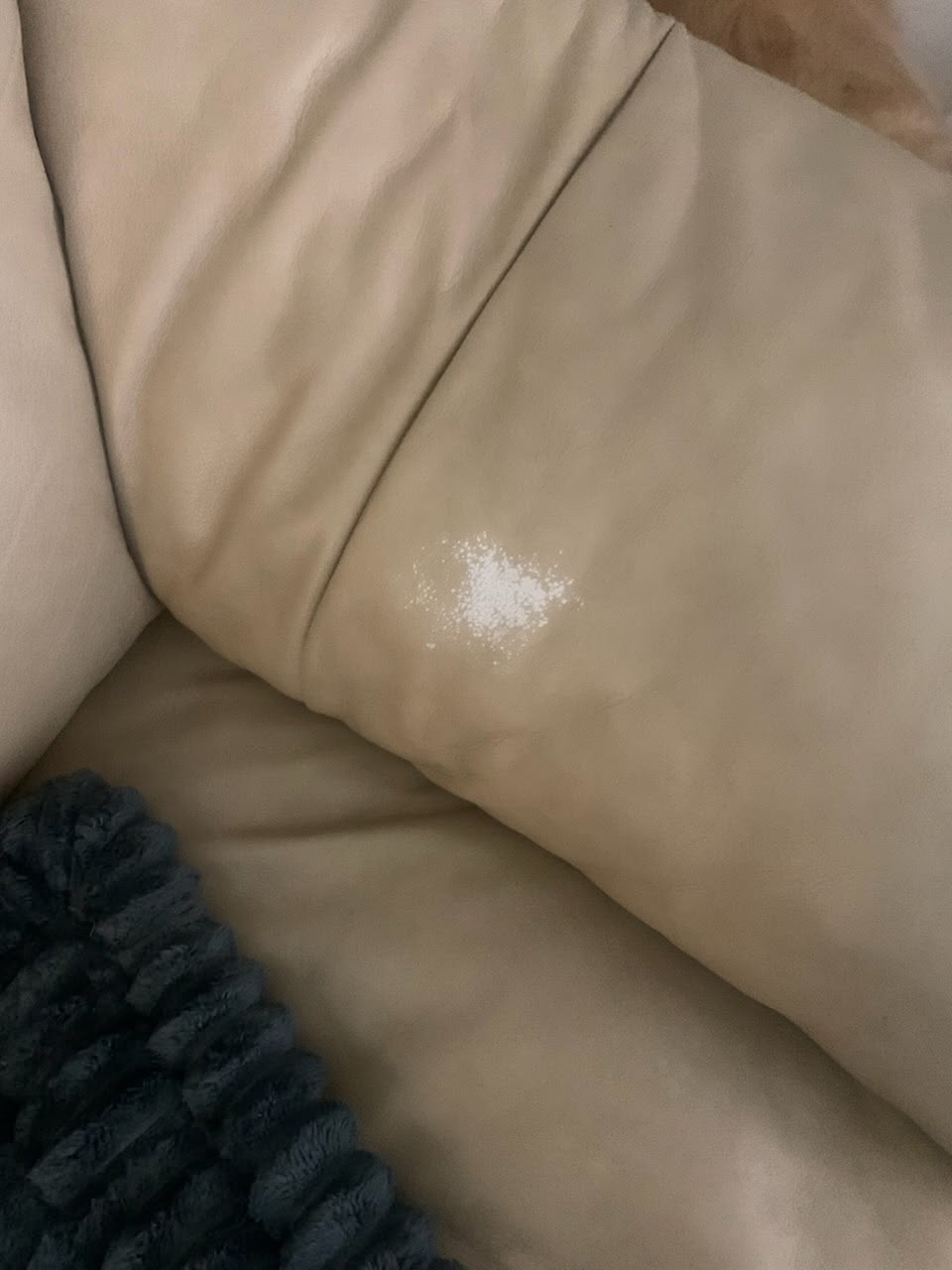 Beige leather sofa with a worn white patch on the cushion