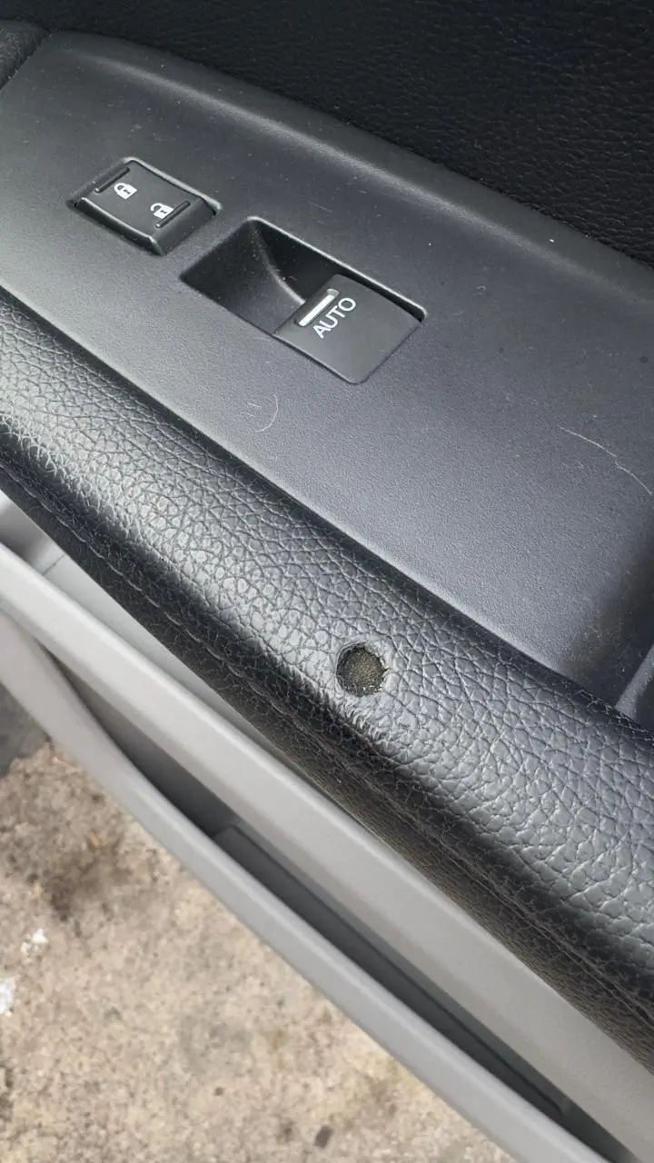 Black car door card with a gouge below the window switch