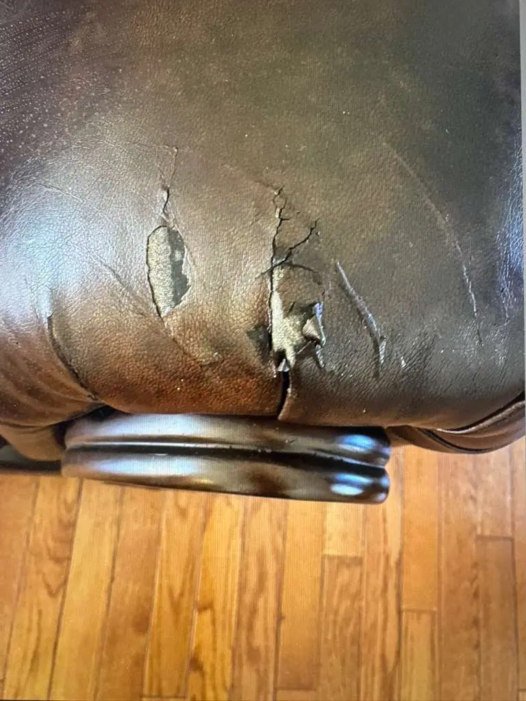 Dark brown leather recliner with deep cracks and flaking finish