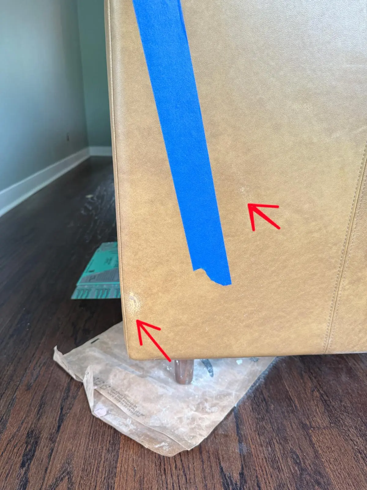 Tan leather sofa corner with worn patches marked for repair